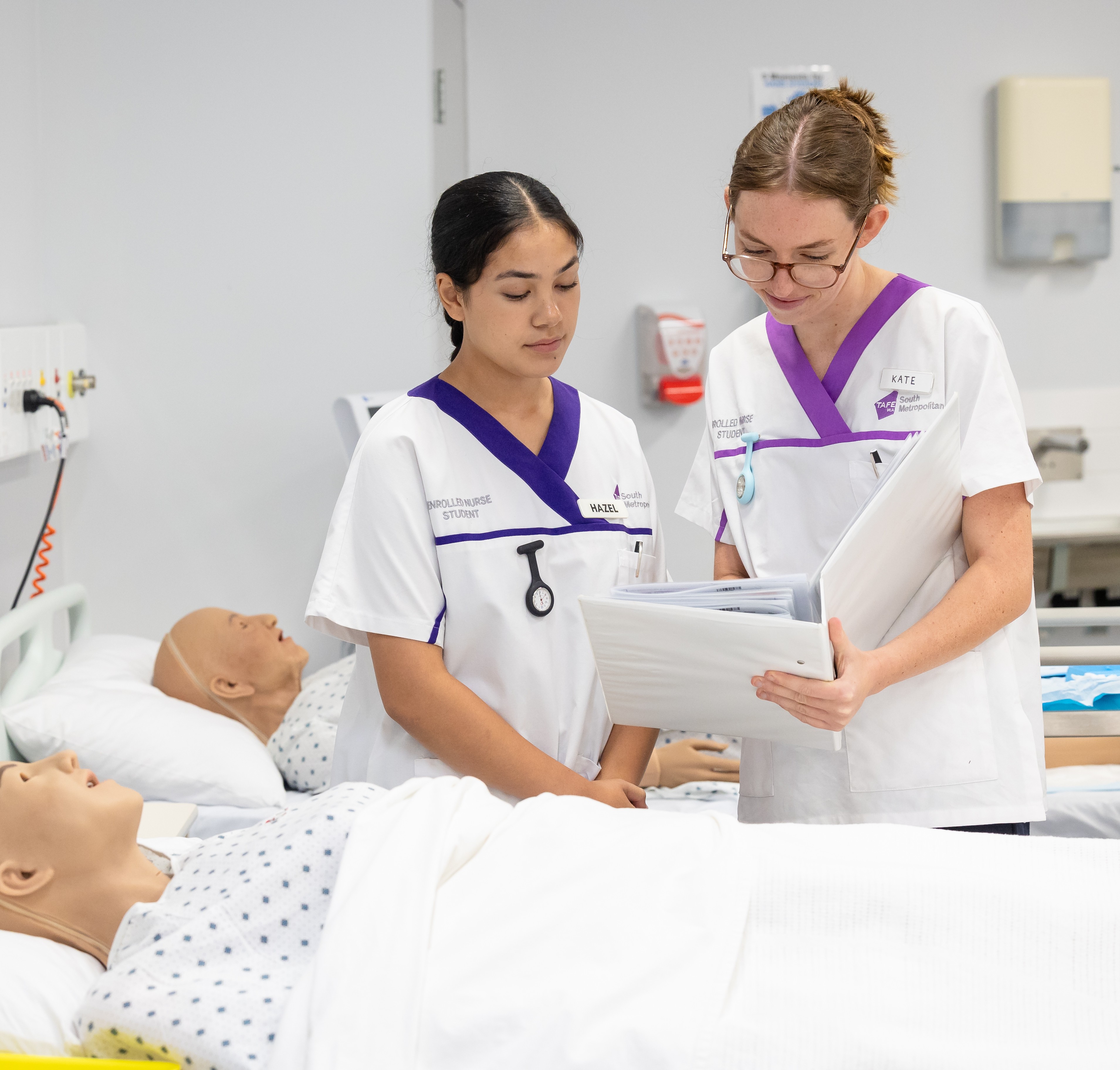 Two nursing students reading a file.
