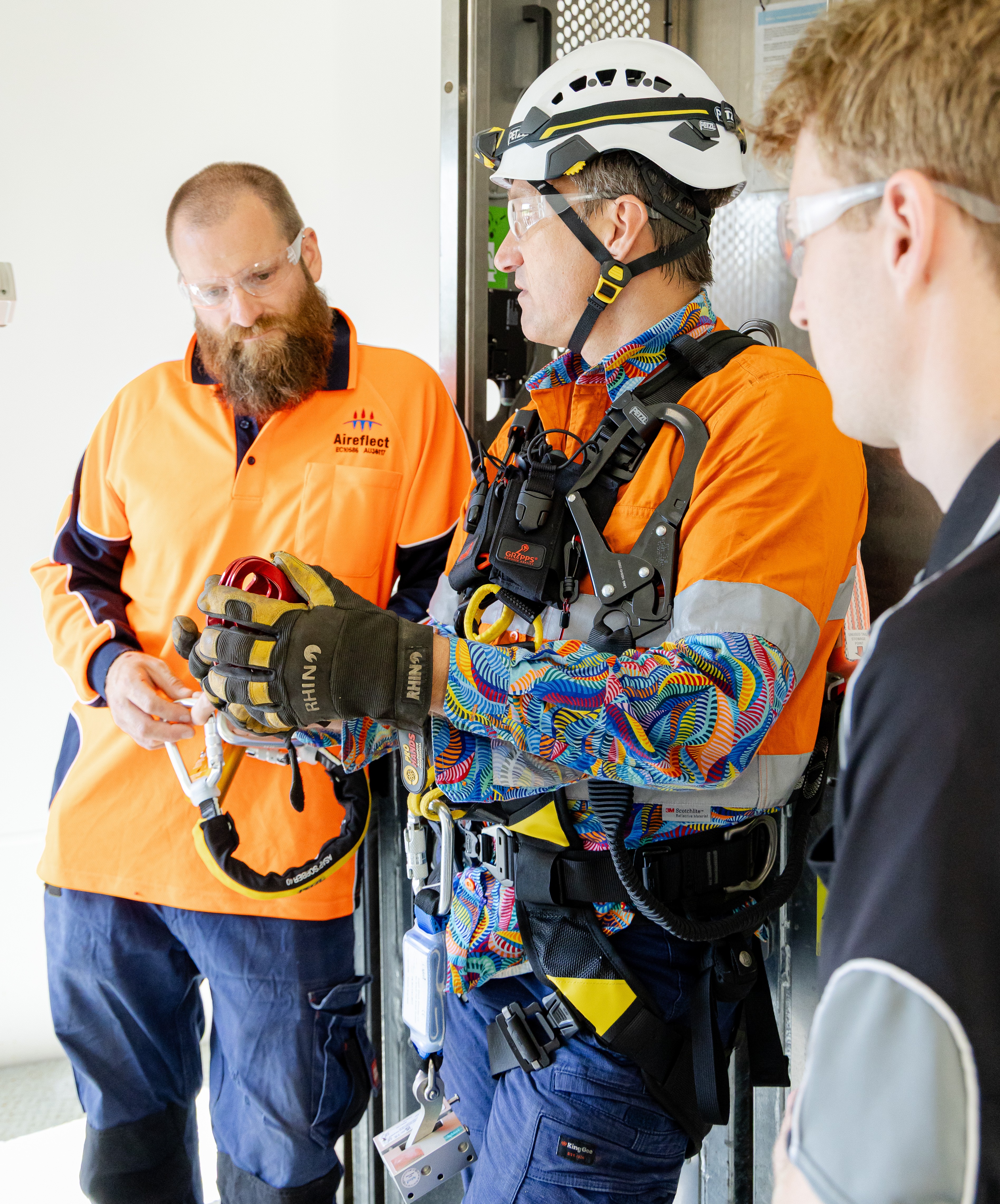 Two students talking to their TAFE lecture who is in high vis. 