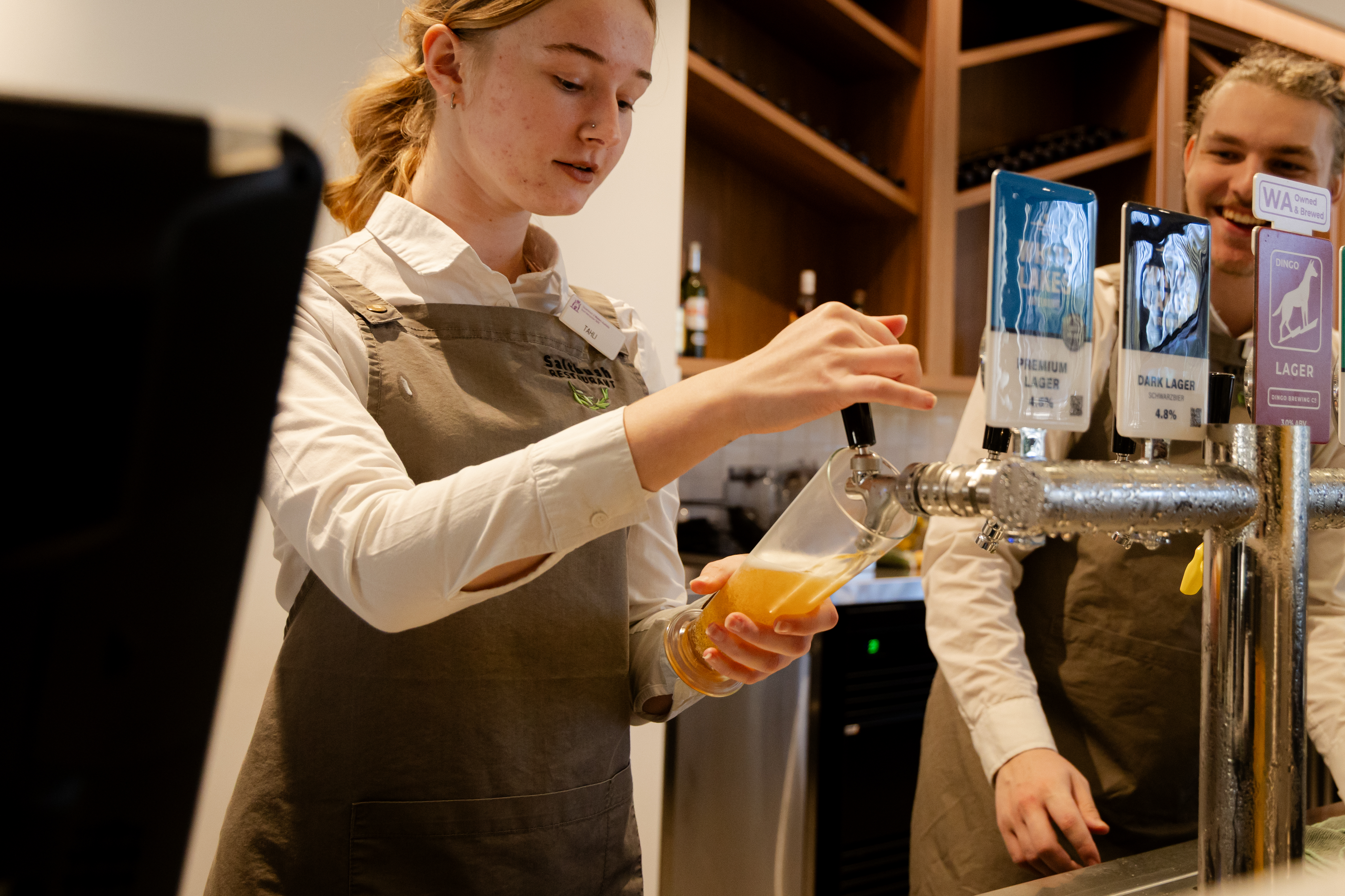 Hospitality student pouring alcohol.