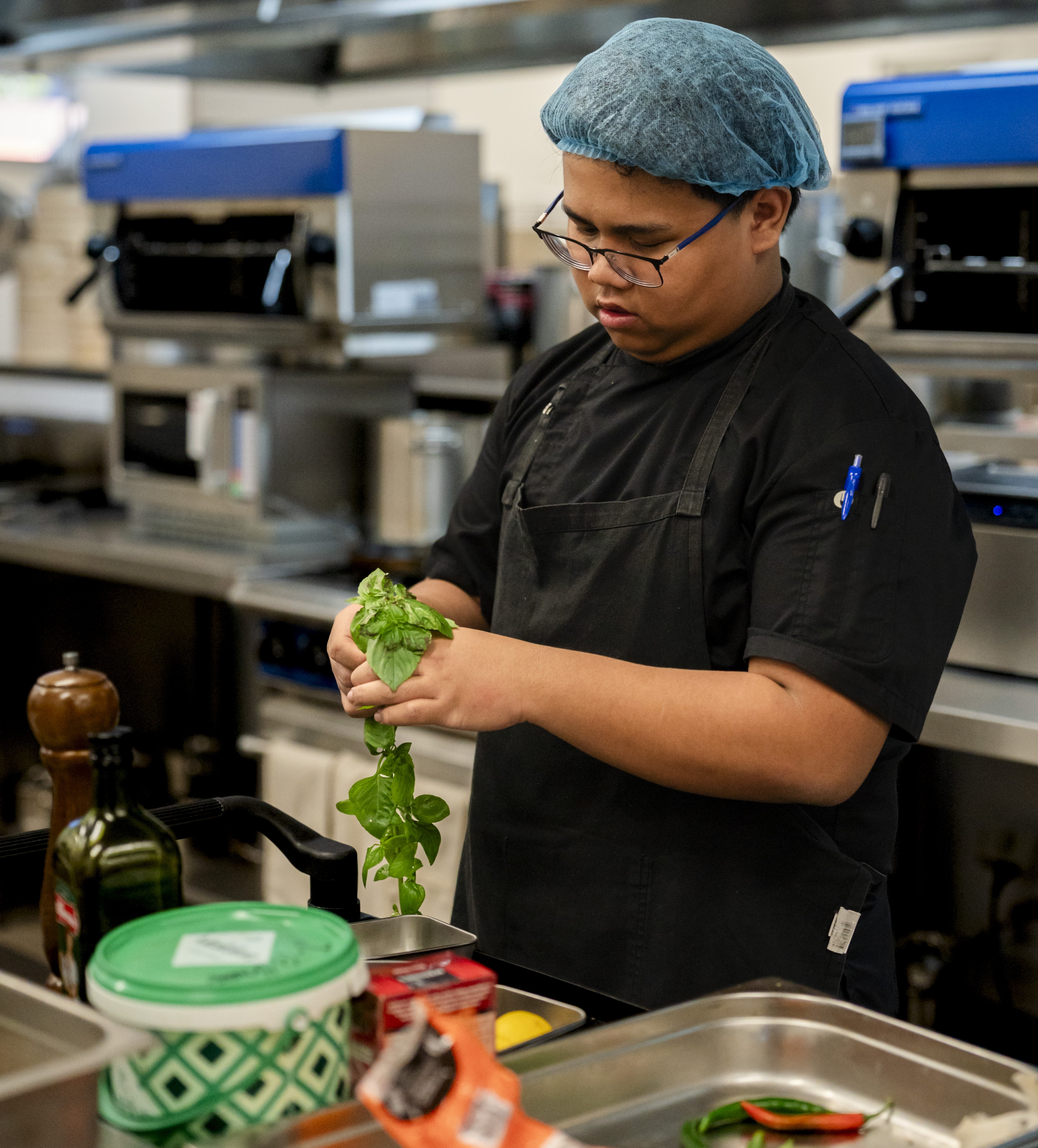 TAFE chef student picking up herbs.