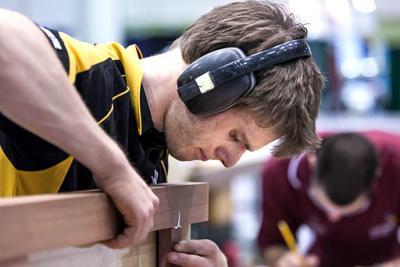 Male gluing two pieces of wood together.