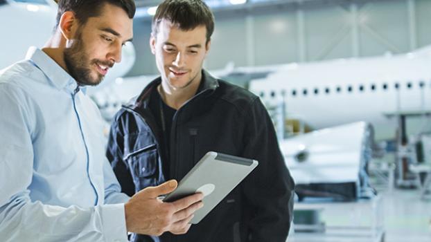 Two engineers looking at an iPad in an aircraft hangar