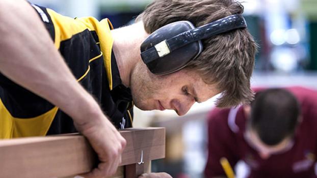 Male gluing two pieces of wood together.