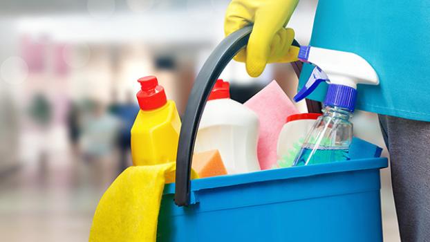 Gloved hand holding a bucket containing cleaning products