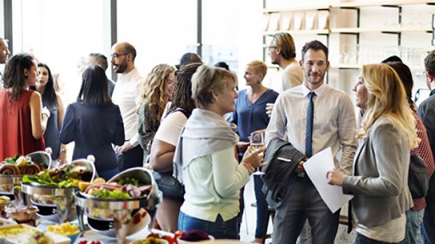 Group of people at an event with a table of food.