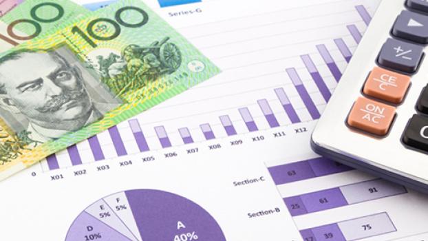 Money and graphs located on a desk with a calculator