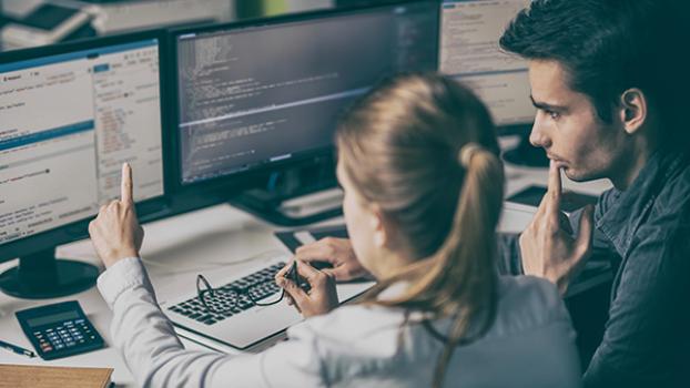 Two front end web developers looking over code on a screen