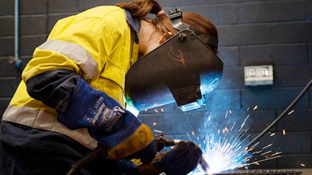 Female welder using tools to weld.
