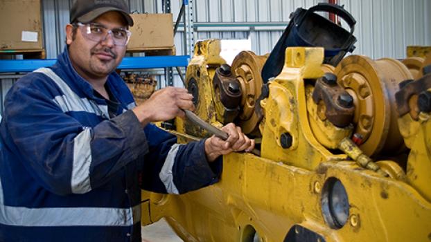 Male plant mechanic with heavy metal machine.