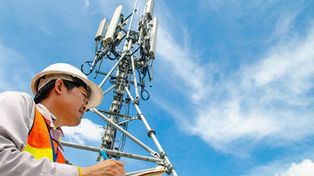 Telecommunications tower with technician looking over.