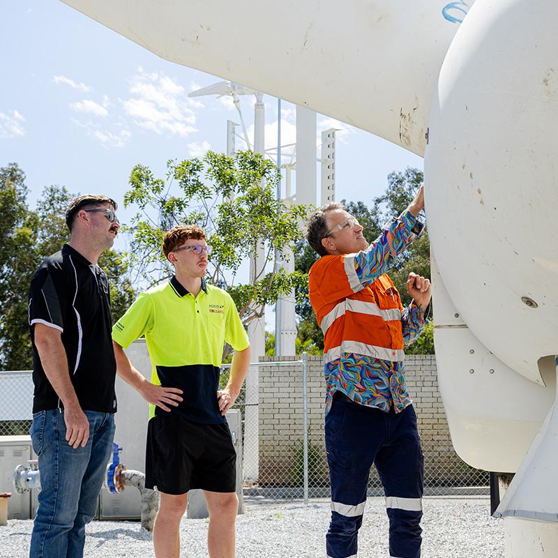 two students watching the lecturer show them the clean energy equipment