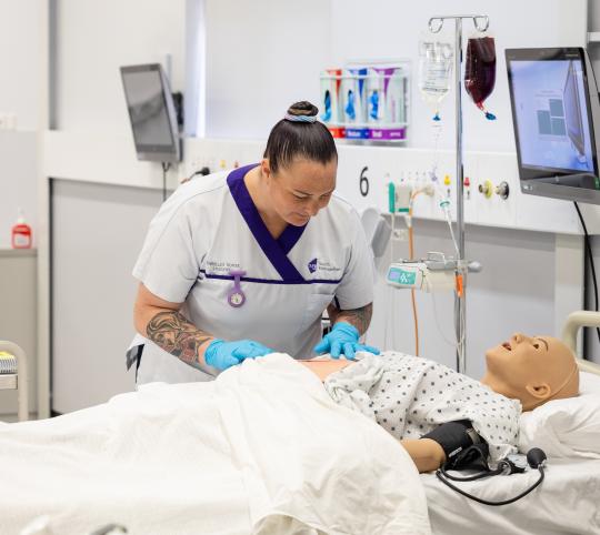 Female enrolled nurse pretending to check on pretend patient doll,