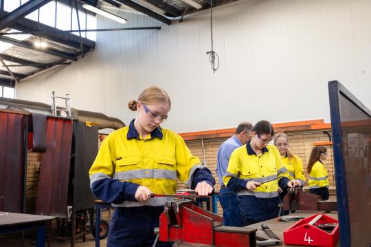 Heavy fabrication student using tools on work bench.