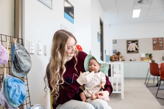 Child care worker student holding baby doll.