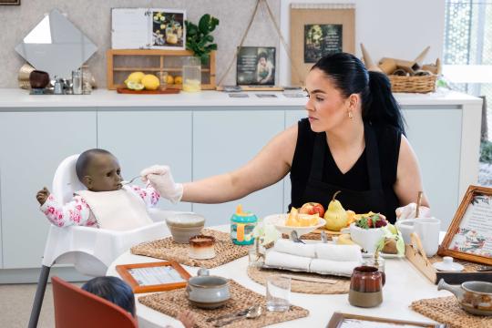 Female child care worker pretending to feed baby doll.