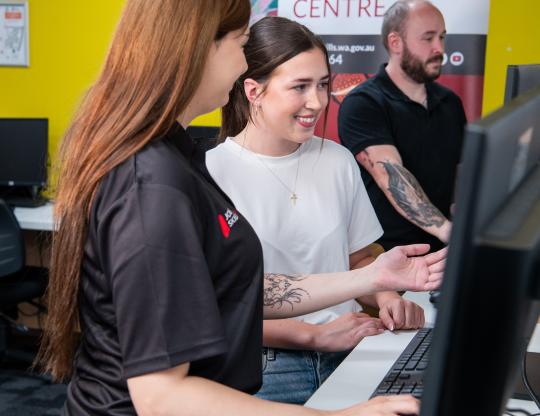 JSC staff member helping student on computer.