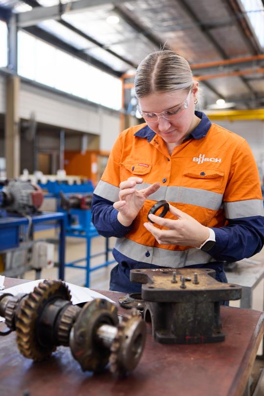 Machinist using hand tools in workshop.