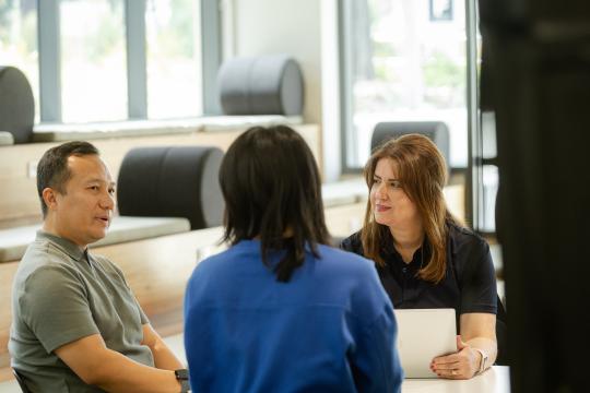 Migration Services staff members talking to student at desk. 