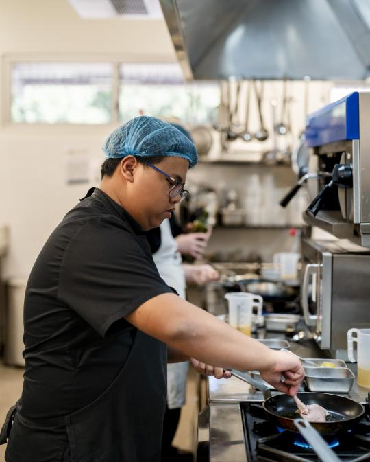 Chef student cooking over stove.
