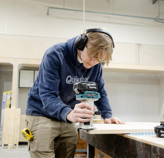 Cabinet making student sanding wood. 