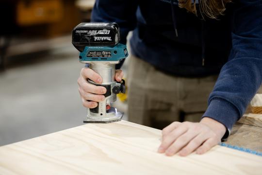 TAFE student holding cabinet making tool.