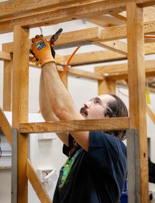 Electrician apprentice putting up a cable.