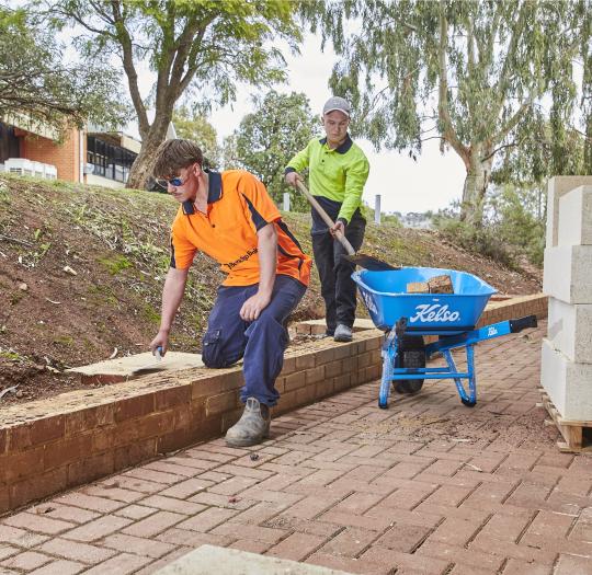 Two construction students laying bricks.