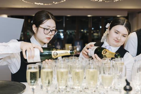 Two female bartenders pouring champagne.
