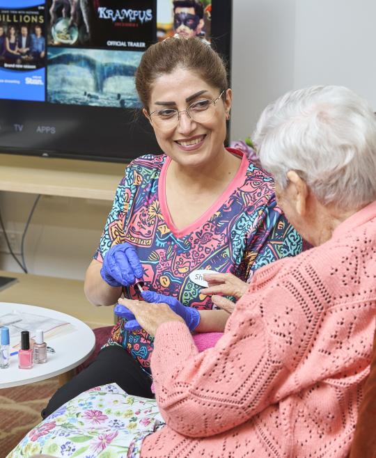 Aged care worker giving massage to elderly client.