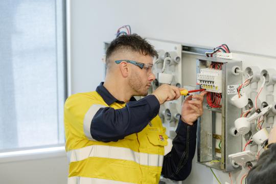 Industrial electrician student working on electrical board.