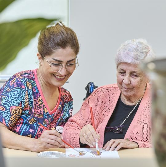 Aged care worker colouring in with elderly client.
